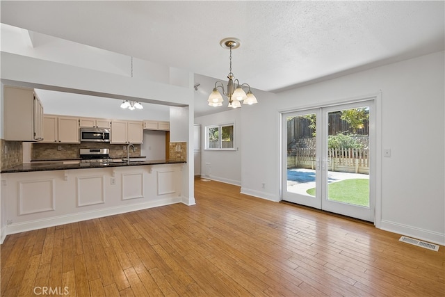 kitchen with hanging light fixtures, appliances with stainless steel finishes, plenty of natural light, and a notable chandelier