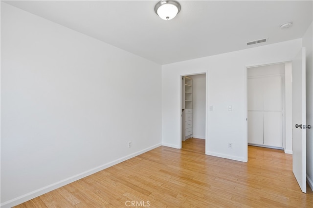 unfurnished bedroom featuring light hardwood / wood-style flooring, a closet, and a spacious closet