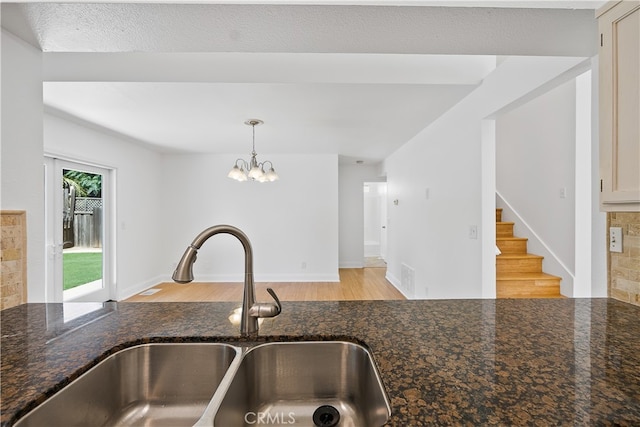 kitchen with pendant lighting, sink, a textured ceiling, dark stone counters, and light hardwood / wood-style floors