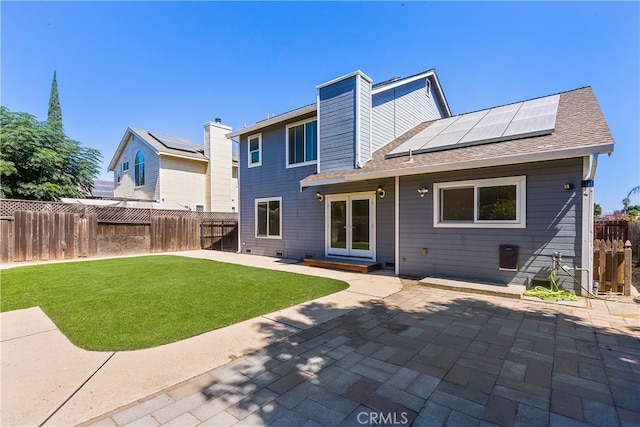 back of property with a patio, solar panels, and a yard