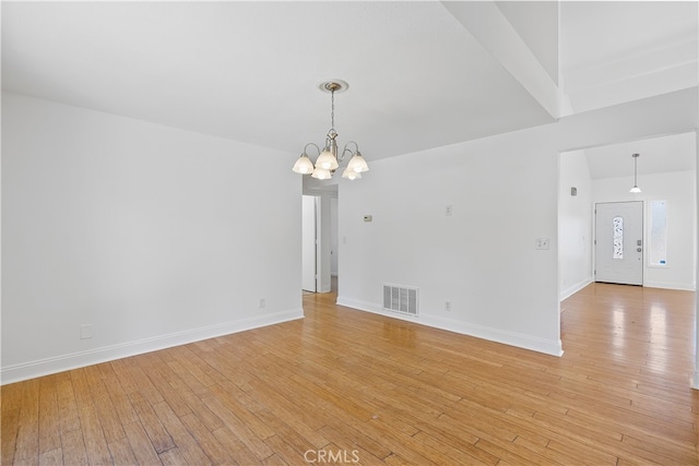 unfurnished room with a chandelier and light hardwood / wood-style floors