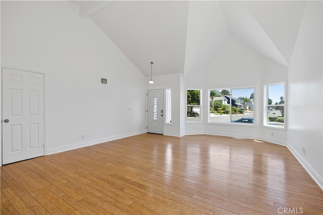 unfurnished living room featuring beam ceiling, light hardwood / wood-style floors, and high vaulted ceiling