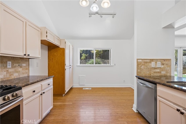 kitchen with dark stone counters, stainless steel appliances, and plenty of natural light