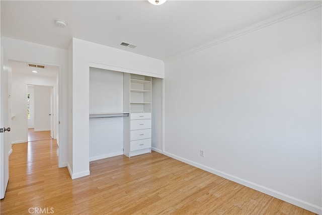 unfurnished bedroom with ornamental molding, a closet, and light hardwood / wood-style floors