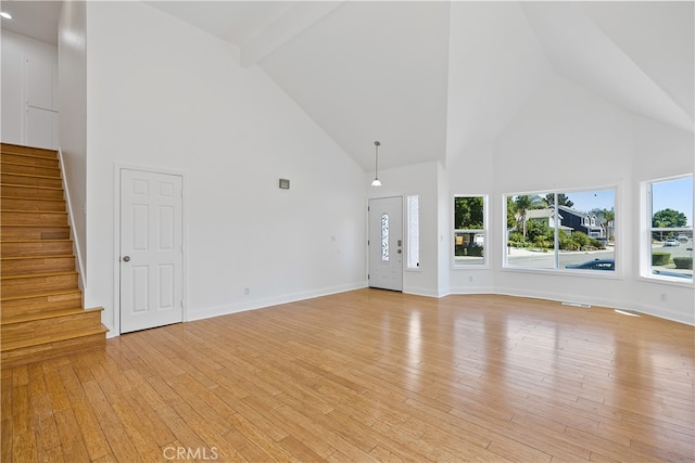 unfurnished living room with high vaulted ceiling, beamed ceiling, and light hardwood / wood-style flooring