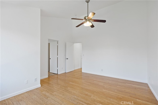 empty room featuring light wood-type flooring, ceiling fan, and high vaulted ceiling