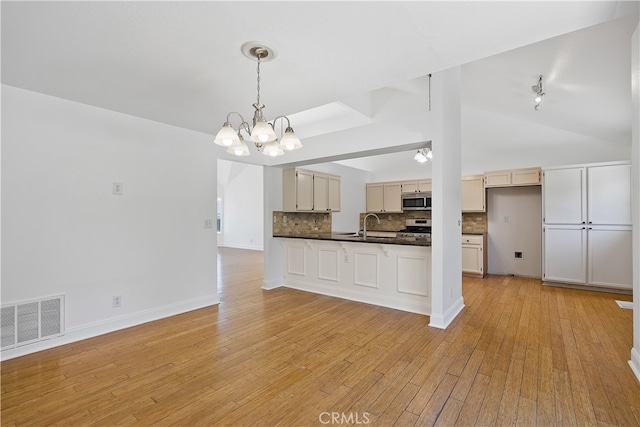 kitchen with backsplash, pendant lighting, stainless steel appliances, light hardwood / wood-style flooring, and a notable chandelier