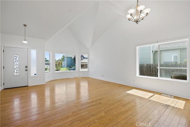 entrance foyer with a notable chandelier, light wood-type flooring, and high vaulted ceiling