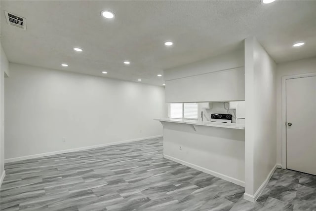 kitchen featuring black stove, a breakfast bar, white cabinets, kitchen peninsula, and white fridge with ice dispenser