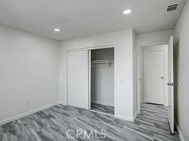 unfurnished bedroom featuring light hardwood / wood-style floors, a closet, and a textured ceiling