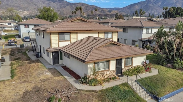 view of front of house with a mountain view, cooling unit, and a front lawn