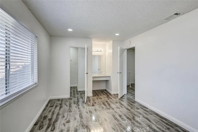 unfurnished bedroom with light hardwood / wood-style floors, a textured ceiling, and a closet