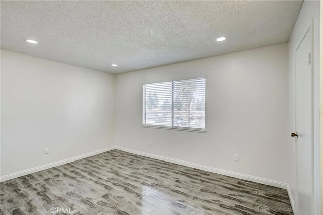 unfurnished room with wood-type flooring and a textured ceiling