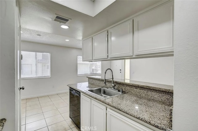 kitchen with light stone countertops, dishwasher, sink, light tile patterned floors, and white cabinets