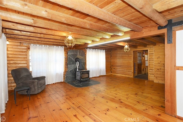 unfurnished room with beamed ceiling, wood-type flooring, a wood stove, and wooden ceiling