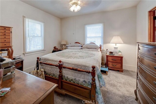 bedroom with multiple windows, ceiling fan, and dark carpet