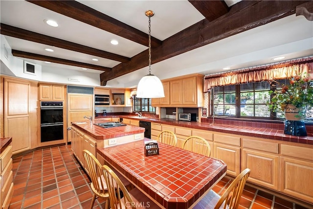 kitchen featuring decorative light fixtures, beamed ceiling, a kitchen island with sink, and tile countertops