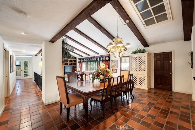 dining space with dark tile patterned floors, lofted ceiling with beams, and a chandelier