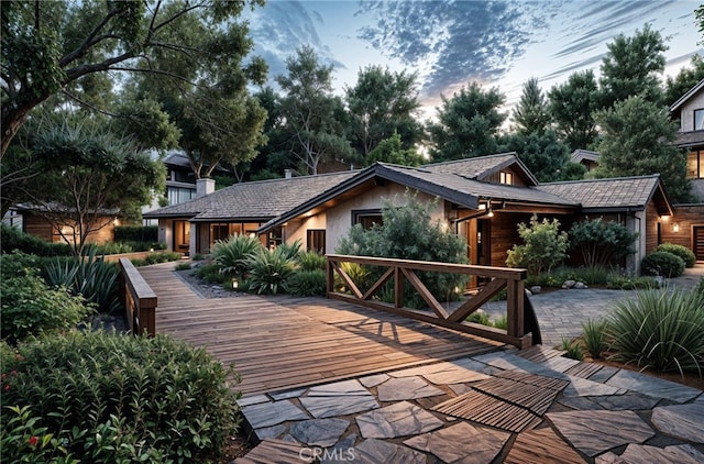 back house at dusk with a deck and a patio area