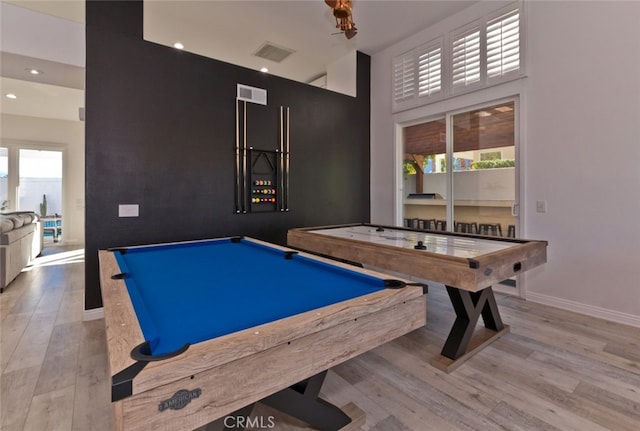 recreation room with visible vents, wood finished floors, recessed lighting, baseboards, and a towering ceiling