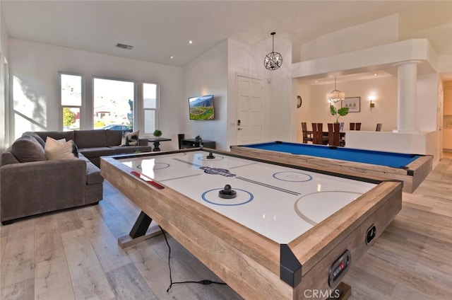 rec room with visible vents, a chandelier, decorative columns, a high ceiling, and light wood-style floors