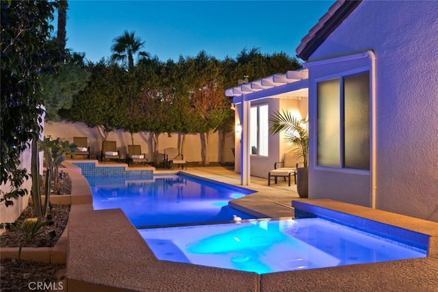 view of swimming pool featuring a pool with connected hot tub, a patio, and fence