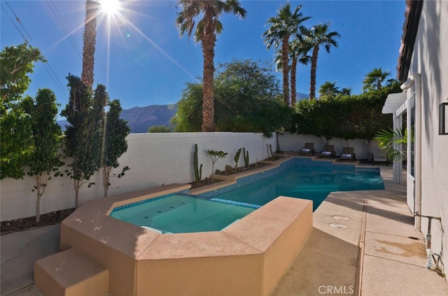 view of swimming pool featuring a fenced backyard, a mountain view, a fenced in pool, an in ground hot tub, and a patio area