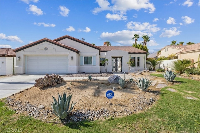 mediterranean / spanish house with concrete driveway, a tiled roof, an attached garage, and french doors