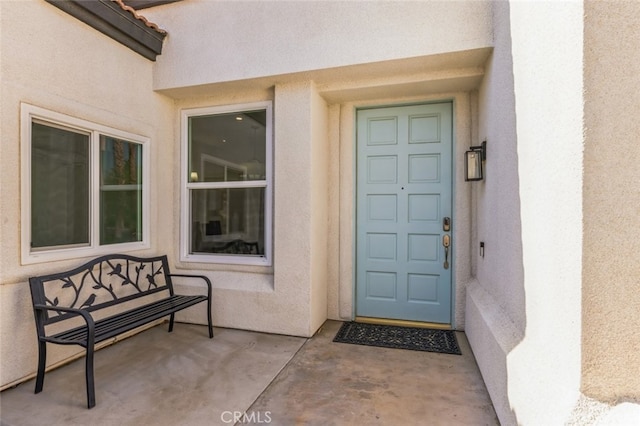 view of exterior entry featuring stucco siding and a tiled roof