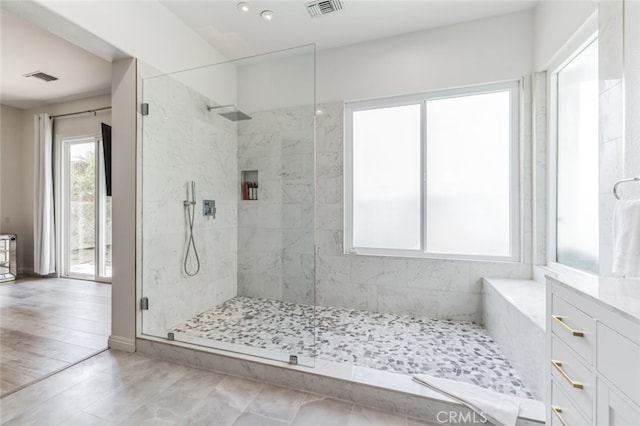 bathroom with a tile shower and visible vents