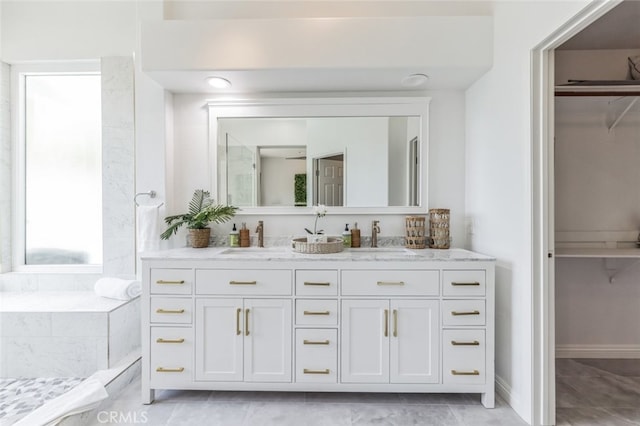 bathroom with double vanity, a spacious closet, and a sink