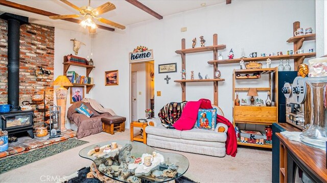 interior space with a wood stove, beamed ceiling, carpet, and ceiling fan