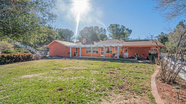 rear view of house with a pergola and a lawn