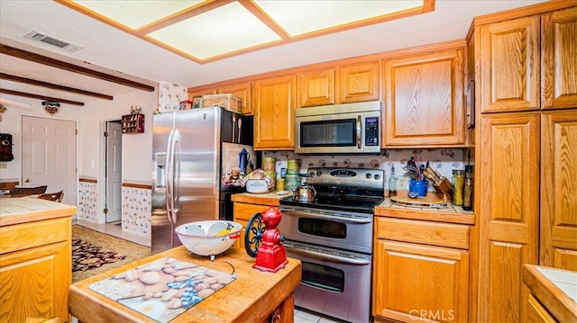 kitchen with stainless steel appliances, tile counters, and beam ceiling