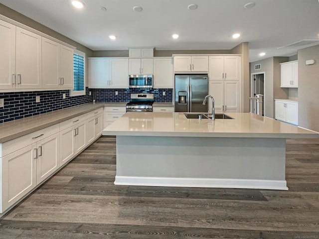 kitchen with a center island with sink, sink, white cabinetry, appliances with stainless steel finishes, and dark hardwood / wood-style flooring