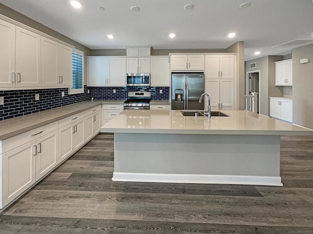 kitchen with sink, dark wood-type flooring, appliances with stainless steel finishes, a kitchen island with sink, and white cabinets