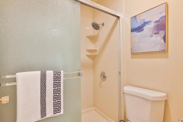 bathroom featuring toilet and a shower with shower door