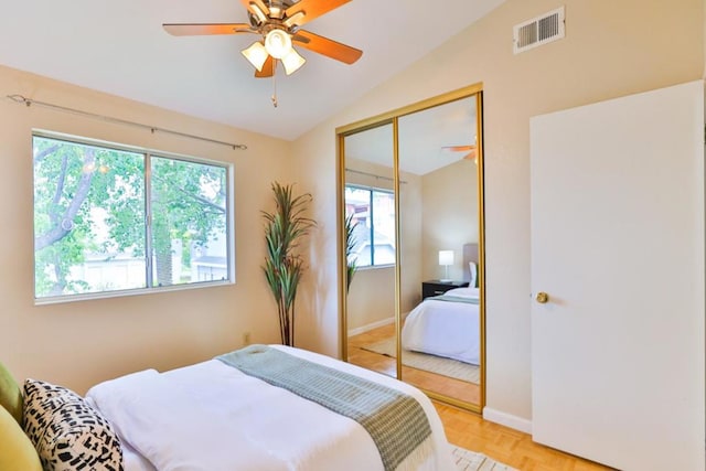 bedroom featuring lofted ceiling, light parquet flooring, multiple windows, a closet, and ceiling fan