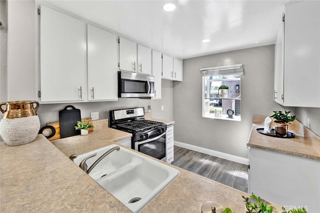 kitchen with hardwood / wood-style flooring, stainless steel appliances, sink, and white cabinets