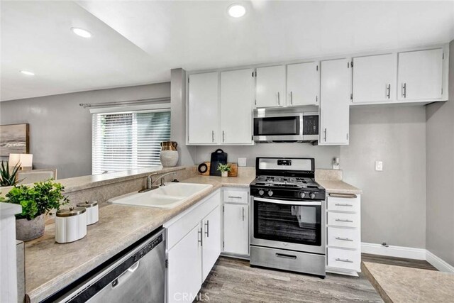 kitchen with sink, stainless steel appliances, white cabinetry, and light wood-type flooring