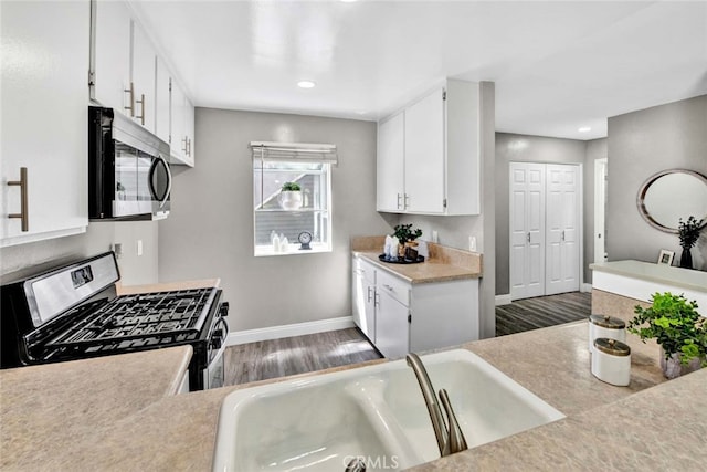 kitchen featuring white cabinets, sink, dark hardwood / wood-style floors, and gas range oven