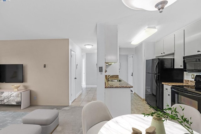 interior space featuring sink, white cabinets, dark stone counters, black appliances, and light carpet