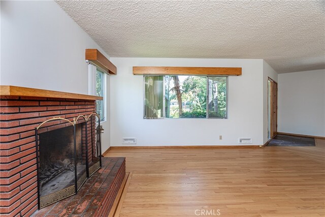 unfurnished living room featuring a textured ceiling, a fireplace, and light hardwood / wood-style flooring