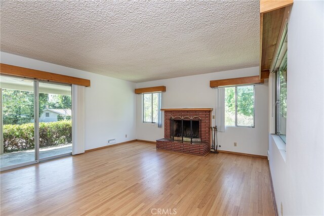 unfurnished living room with a textured ceiling, a fireplace, and light hardwood / wood-style flooring