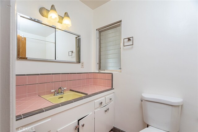 bathroom with vanity, backsplash, and toilet