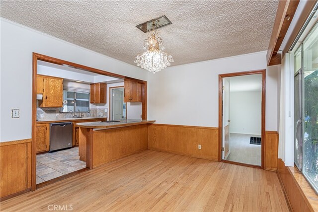 kitchen featuring dishwasher, kitchen peninsula, hanging light fixtures, light hardwood / wood-style flooring, and a healthy amount of sunlight