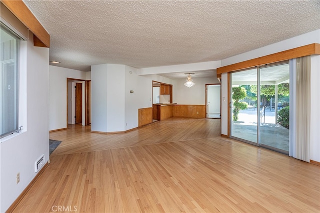 unfurnished room featuring a textured ceiling and light wood-type flooring