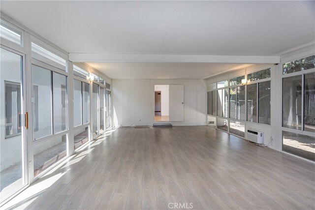 unfurnished room featuring an AC wall unit, wood-type flooring, and expansive windows