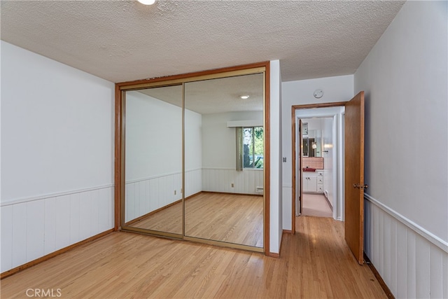 unfurnished bedroom featuring wood-type flooring, a closet, and a textured ceiling