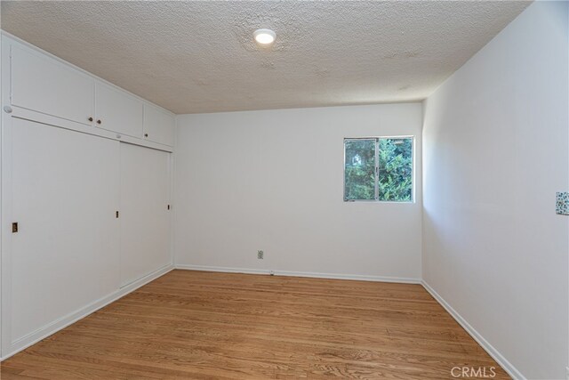 spare room featuring a textured ceiling and light hardwood / wood-style flooring